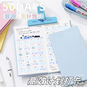 50-day planner notebook set on desk with open habit tracker and light blue cover, ideal for productivity and scheduling in Shopify stationery collection
