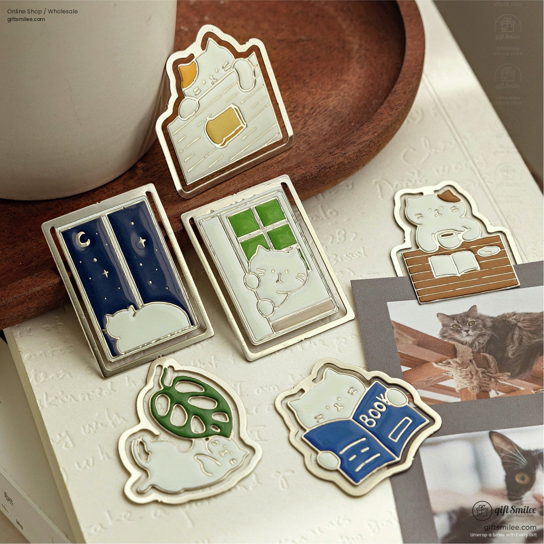 Close-up of cute cat-shaped enamel bookmarks clipped onto book pages.