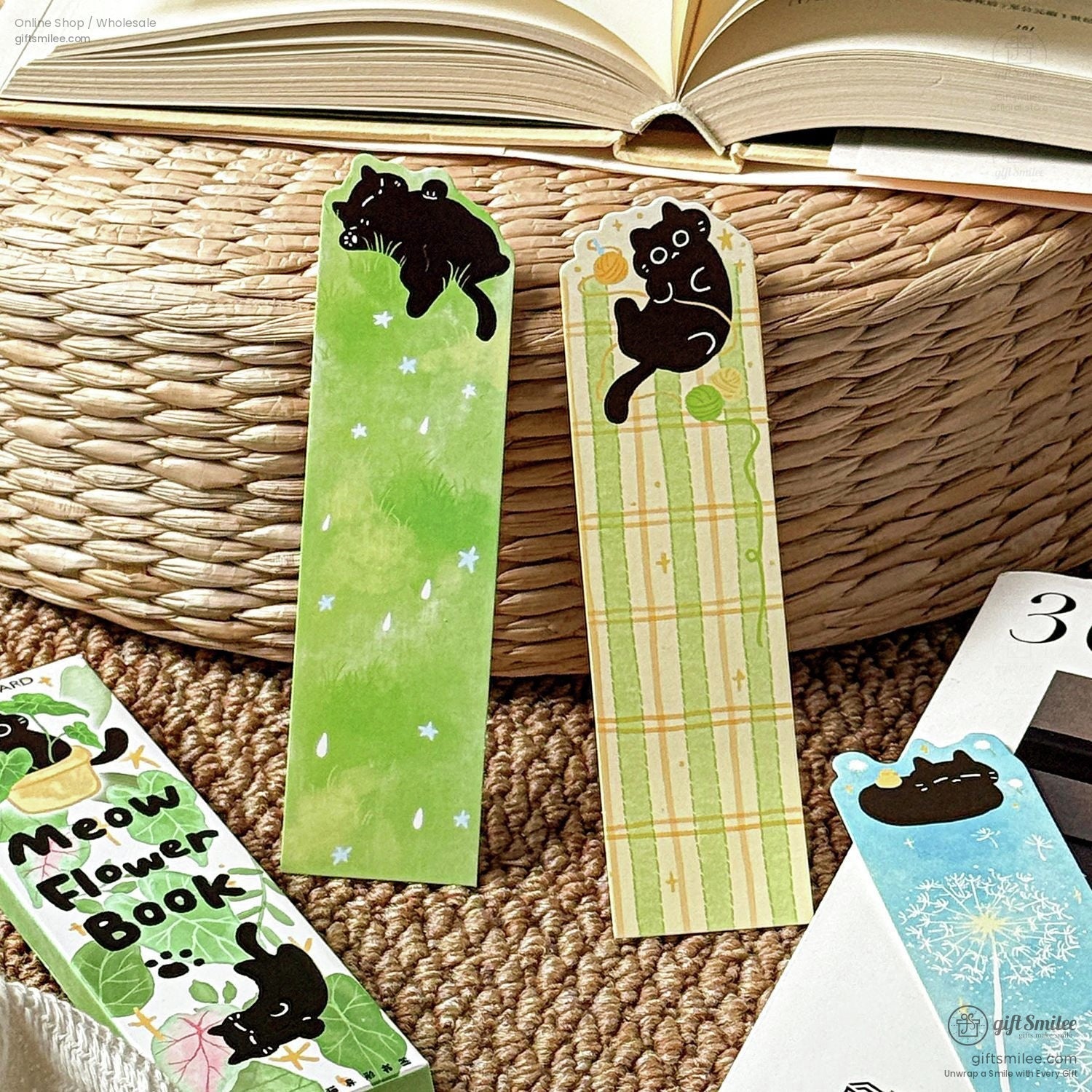 Cute black cat illustrated bookmarks on a woven mat beside an open book – green and plaid designs, kawaii stationery
