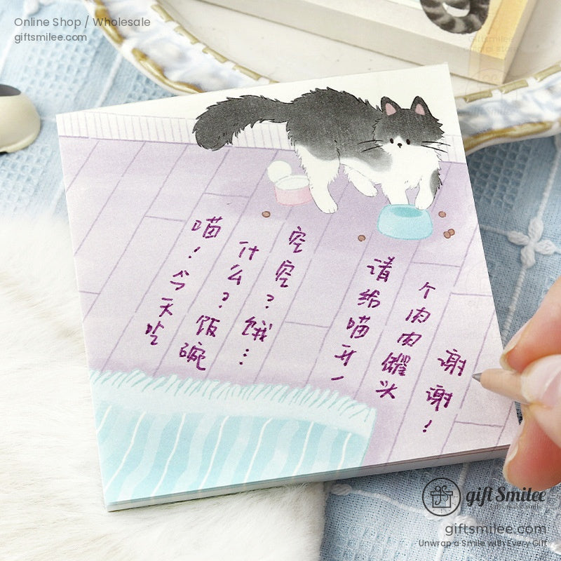 Illustrated notepad with a fluffy black and white cat pastel purple floor blue and pink bowls and handwritten text