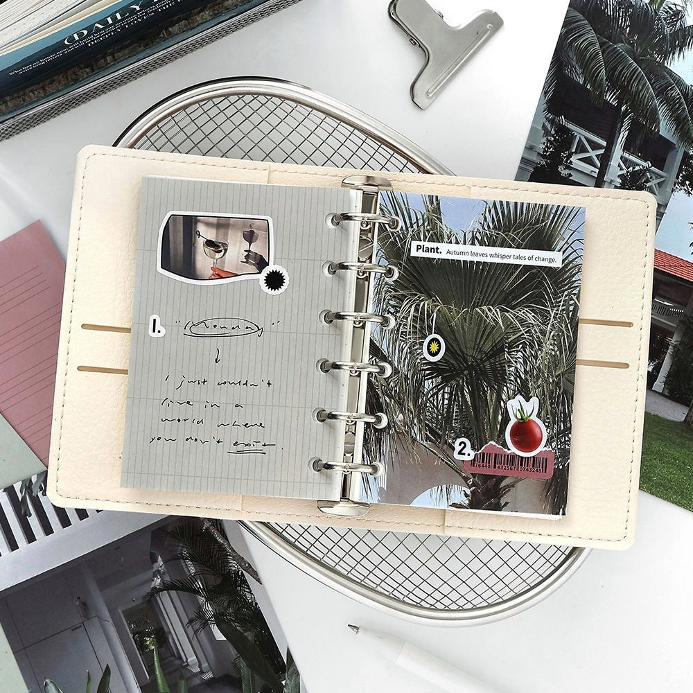 Cream leather planner with metal rings open to aesthetic pages featuring palm tree photo stickers and handwritten notes