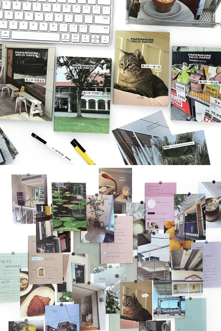 Assorted postcards with pastel tones nature architecture and cat photos arranged with pens and a keyboard nearby