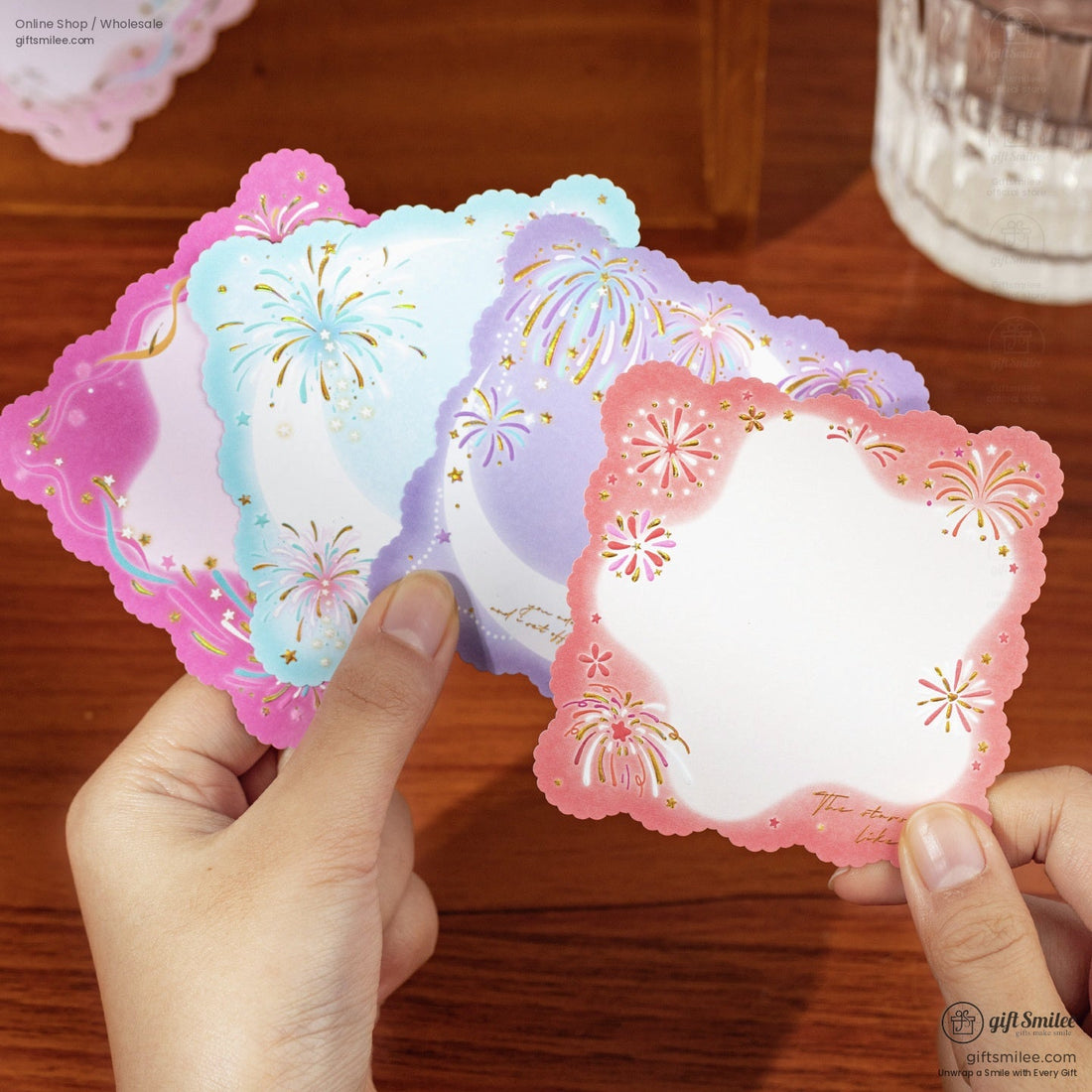 Colorful scalloped note cards in pink blue and purple with gold foil fireworks and star accents held in hand