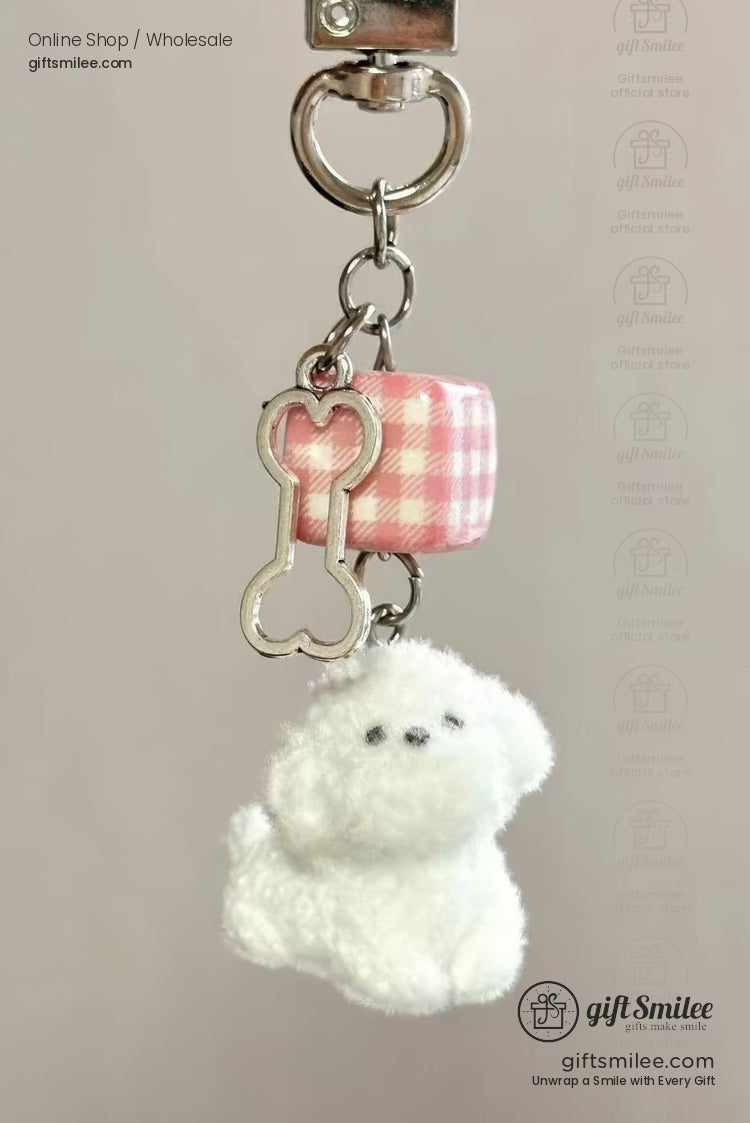Plush white dog charm with silver boneshaped pendant and pink gingham cube attached to a metallic keyring