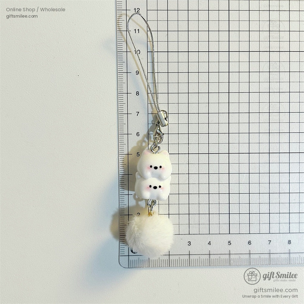 White ceramic charm with stacked cat figures pink cheeks black details fluffy pompom and silver strap attachment