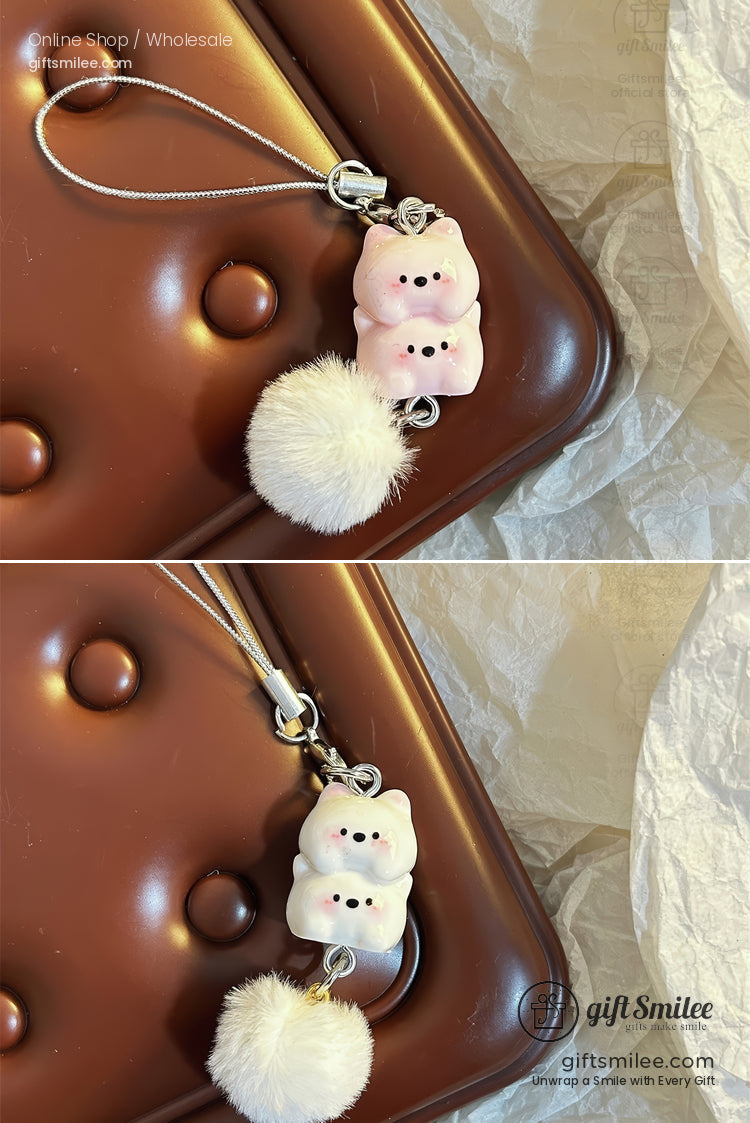 Pink bearshaped charm with black details silver strap and fluffy white pompom on a textured brown surface