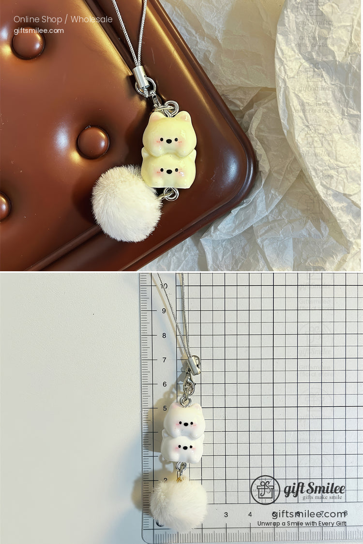 Creamy white bearshaped charm with black details fluffy white pompom silver clasp and braided strap attachment