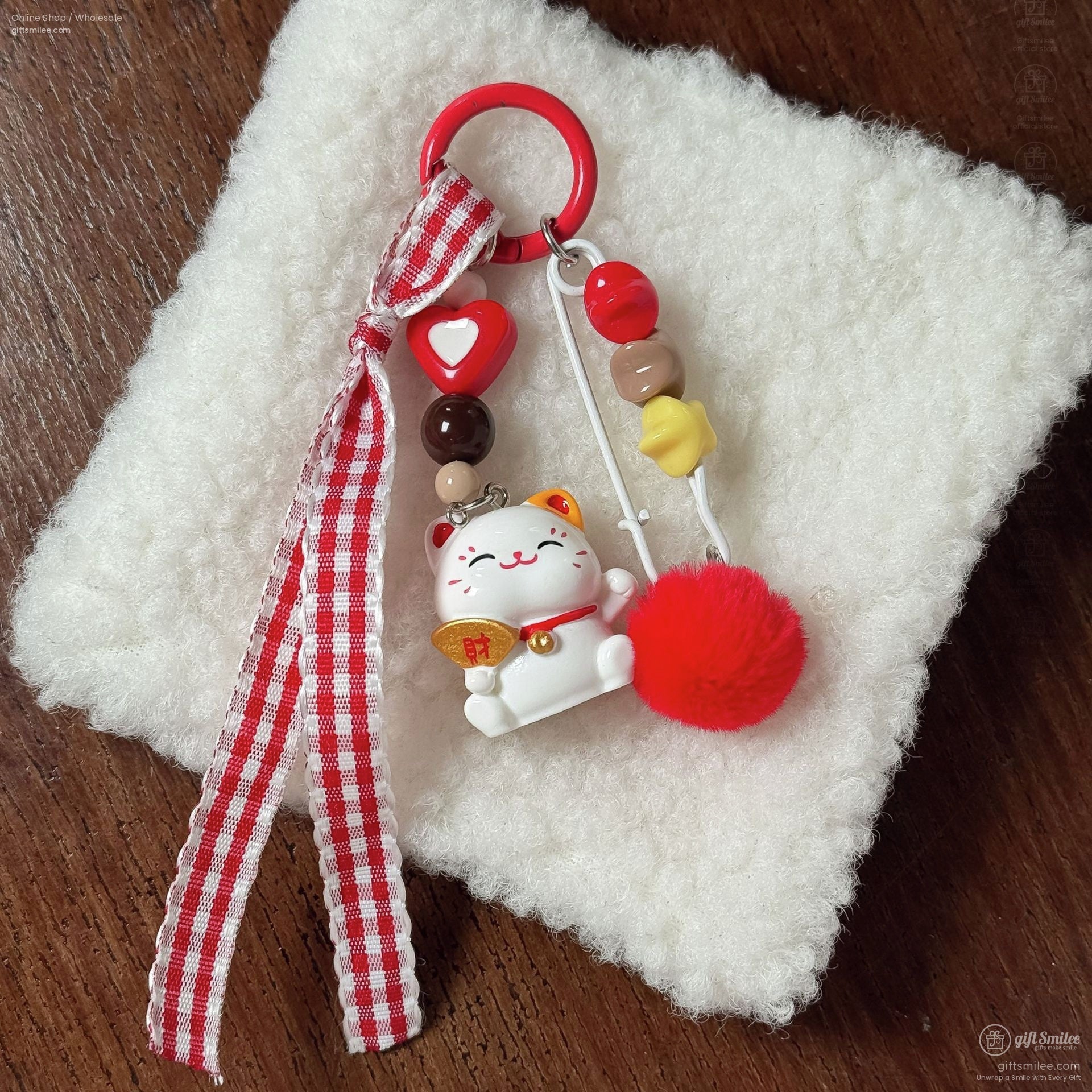 Red and white keychain with checkered ribbon lucky cat charm colorful beads and red fluffy pompom on soft fabric