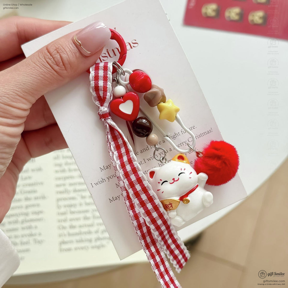 Red and white keychain with checkered ribbon lucky cat charm colorful beads and red fluffy pompom on soft fabric