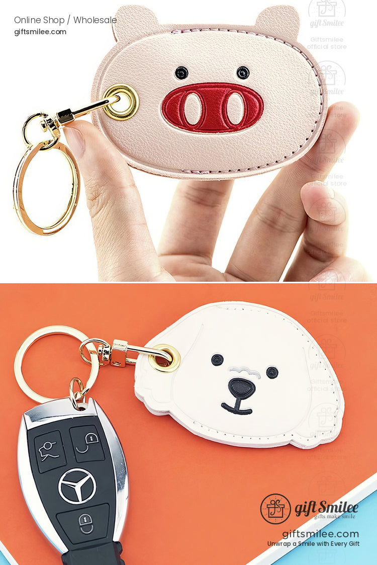 Pink pigshaped leather keychain with red snout detailing and gold keyring paired with white dogshaped leather keychain