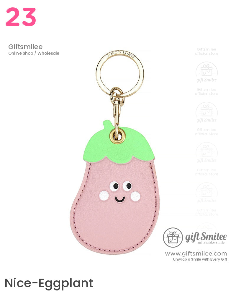 Pink faux leather eggplant keychain with a smiling face green leafy top and gold metal keyring clasp