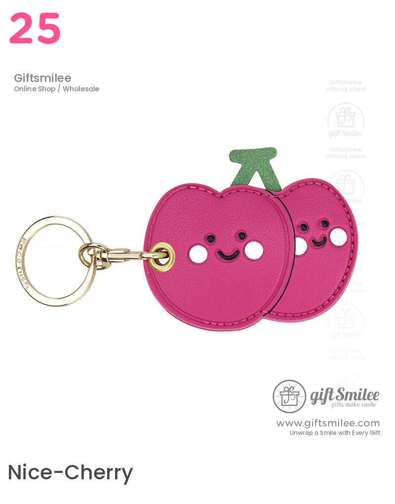 Pink leather cherryshaped keychain with smiling faces green stem detail and goldtone metal keyring attachment