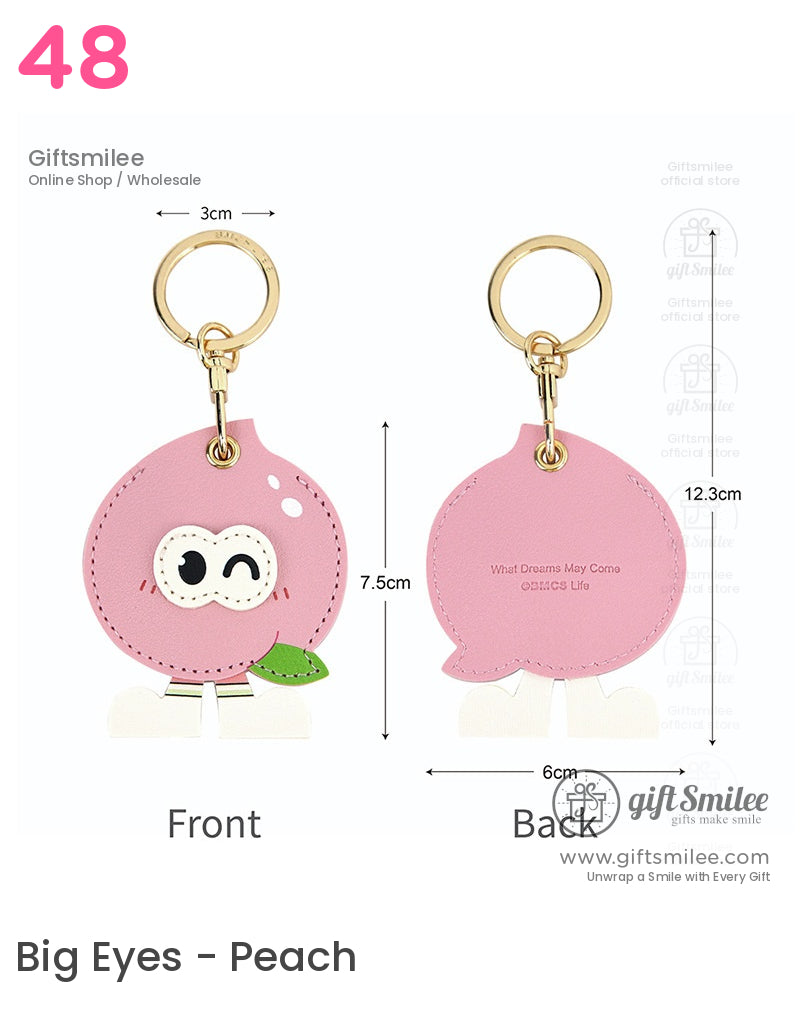 Pink leather peachshaped keychain with winking face gold metal ring green leaf accent and playful white feet