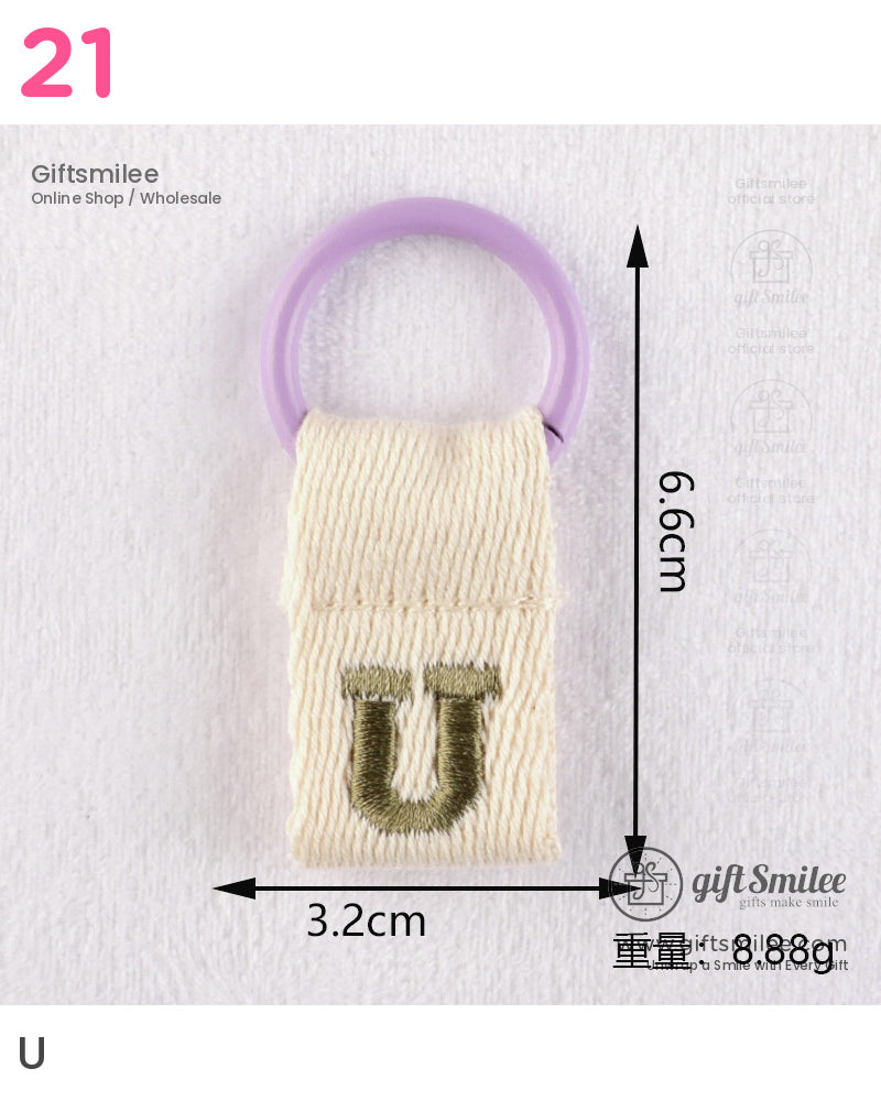 Beige woven fabric keychain with green embroidered U and purple plastic ring measuring 66cm by 32cm
