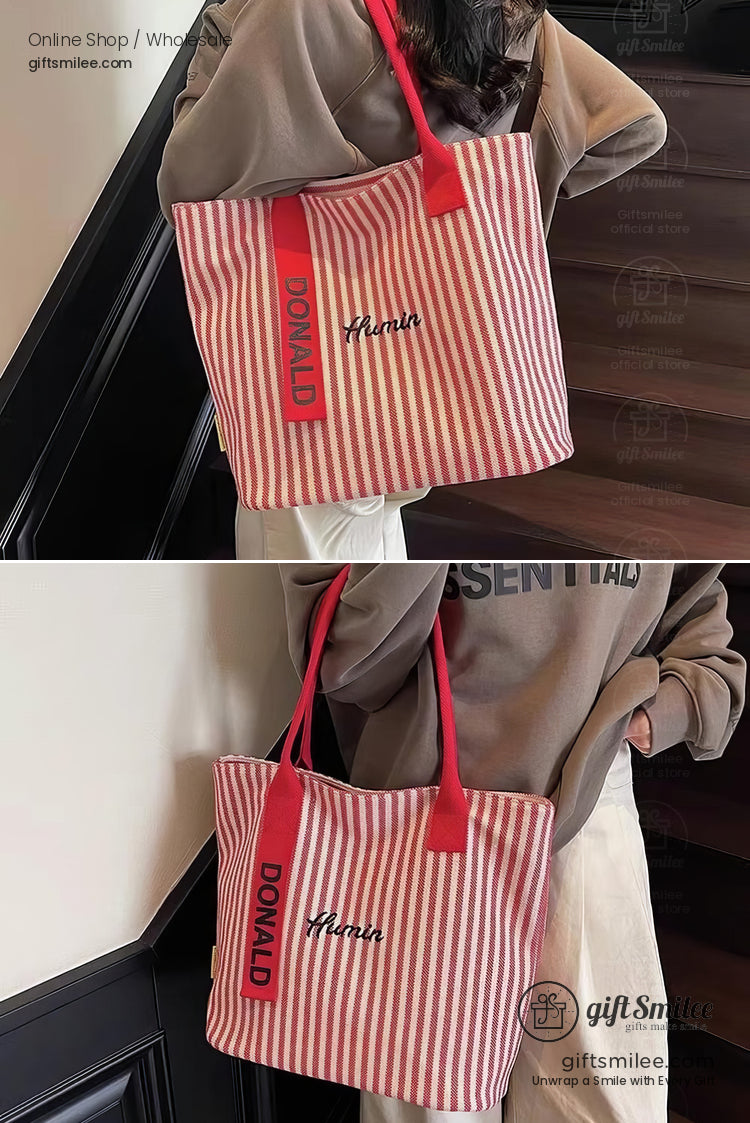 Red and white striped canvas tote bag with bold red handles black embroidered text and casual oversized style