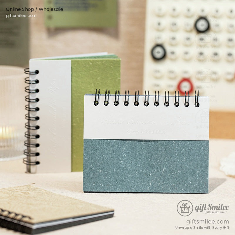 Spiral-bound desktop notebook with textured green and white cover on a minimal workspace, giftsmilee stationery.
