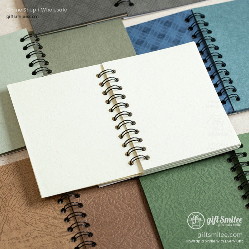 Spiral-bound desktop notebook with textured green and white cover on a minimal workspace, giftsmilee stationery.
