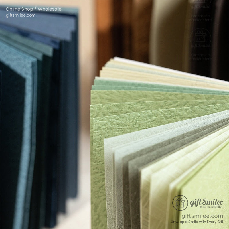 Textured green and neutral cardstock paper samples fanned out for crafting and gift wrapping – GiftSmilee wholesale supplies