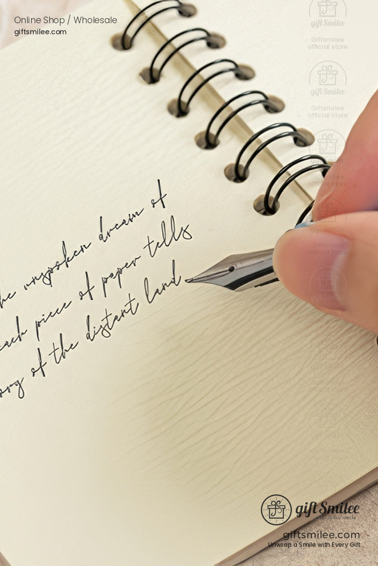 Hand writing cursive text with a fountain pen on a spiral-bound cream notebook.