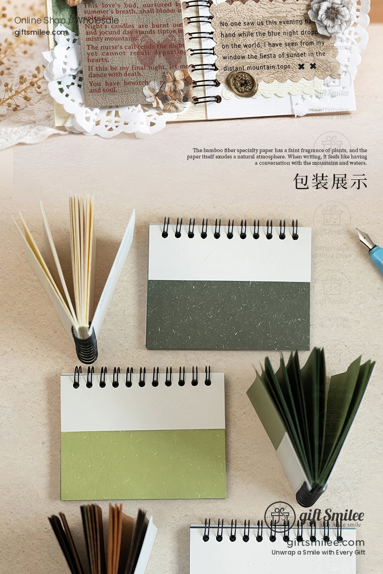 Small spiral-bound kraft notebooks with green and white covers arranged flat and standing, showcasing eco-friendly bamboo paper pages.