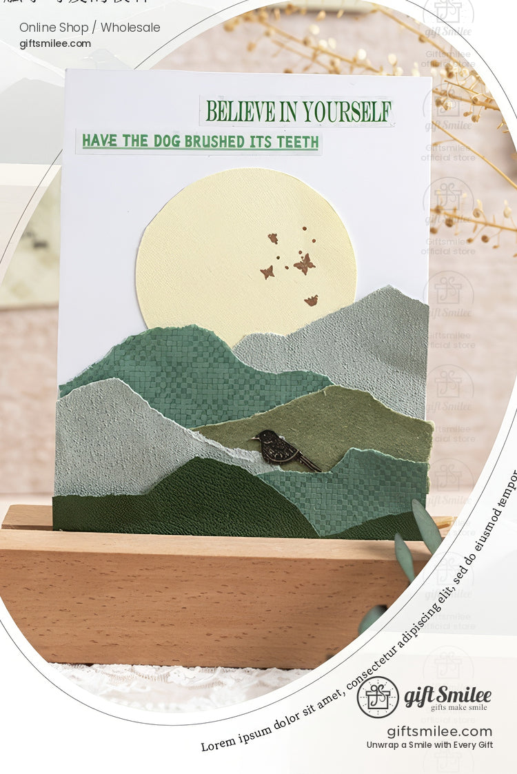 Handmade greeting card with layered green mountain paper art, moon, and “Believe in Yourself” text on wooden stand (giftSmilee stationery).
