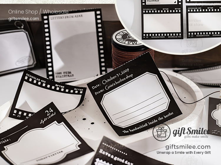 Black-and-white movie clapperboard themed gift tags and labels set displayed on a desk from giftsmilee, cinematic stationery for presents and scrapbooking.