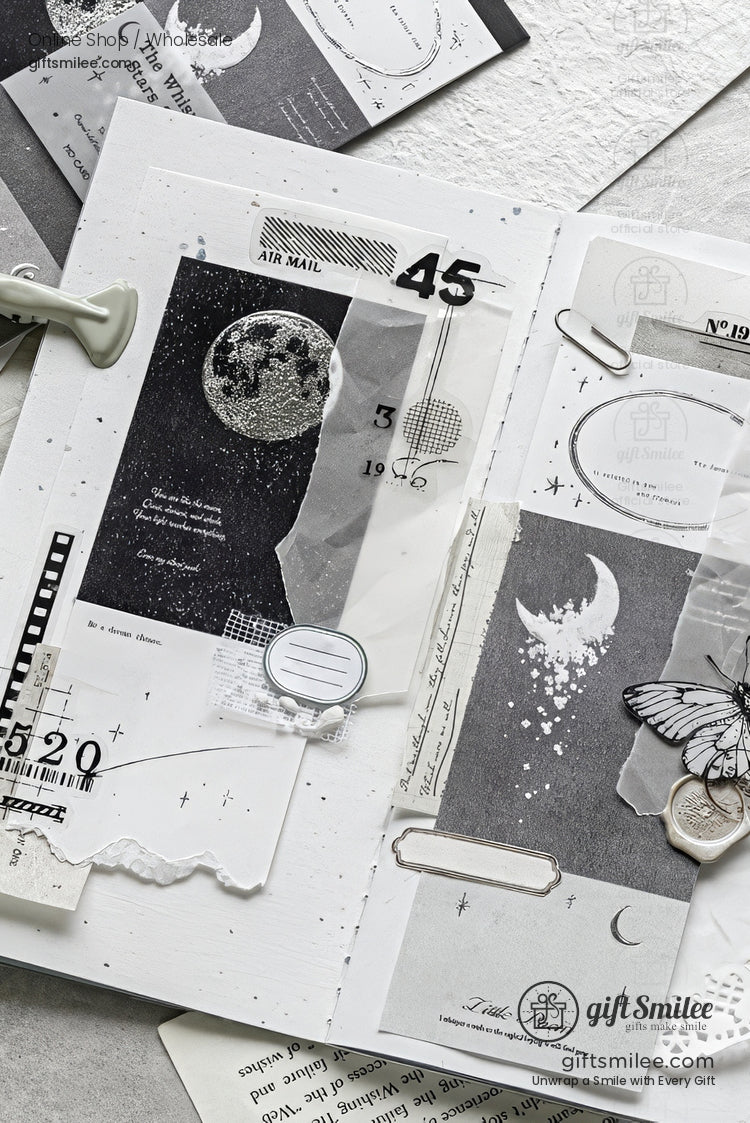 Monochrome celestial scrapbook layout with moon, stars, butterfly charm, and vintage postal ephemera on a white journal page.
