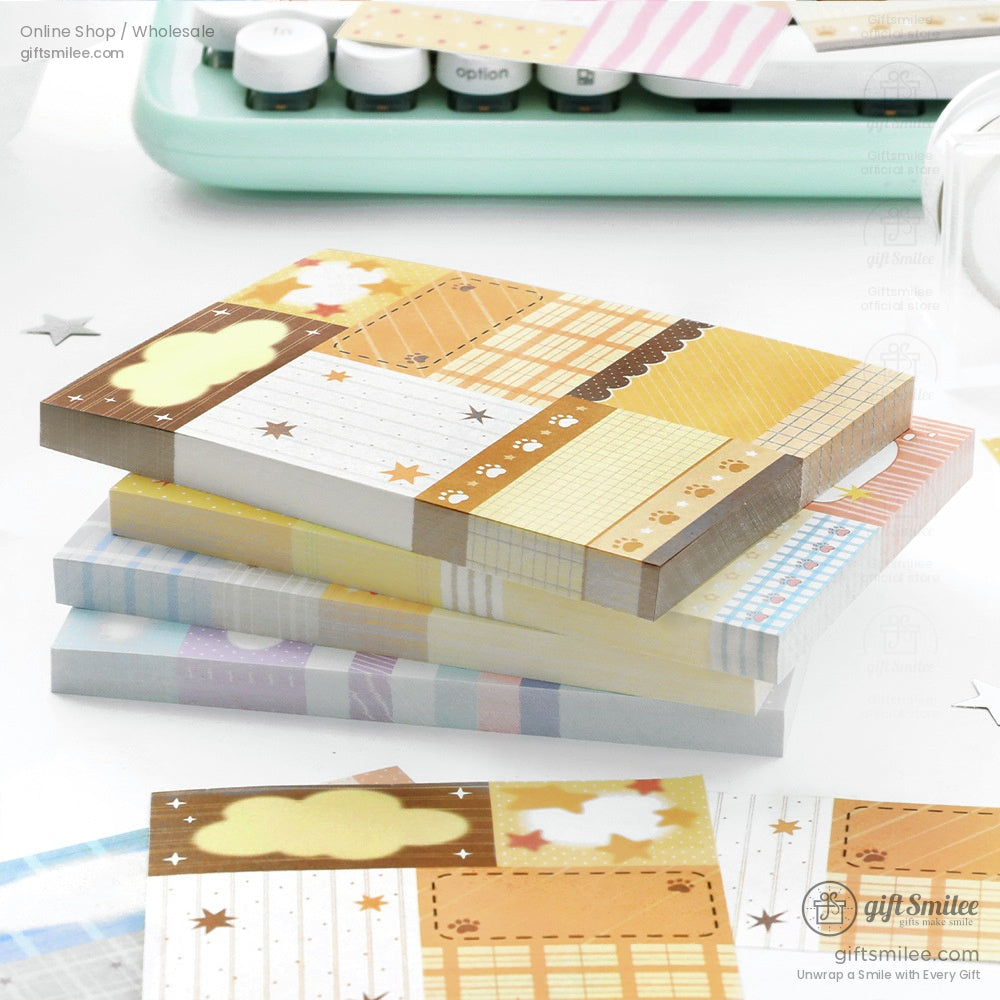 Pastelcolored memo pads with grid stripe and star patterns in blue pink and yellow tones arranged on a white tray