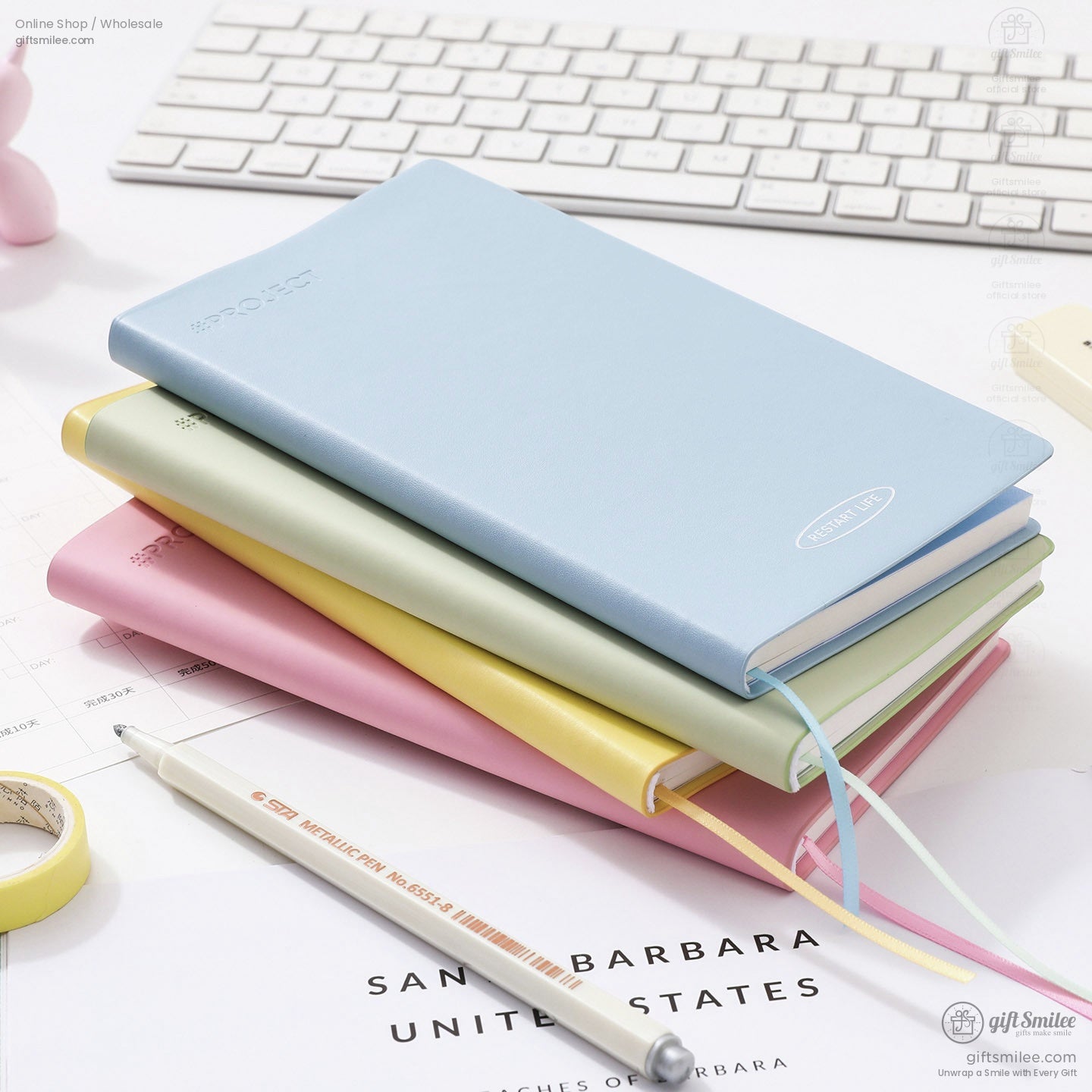 Pastel leather hardcover notebooks stacked on desk near keyboard, ideal for journaling and planning.