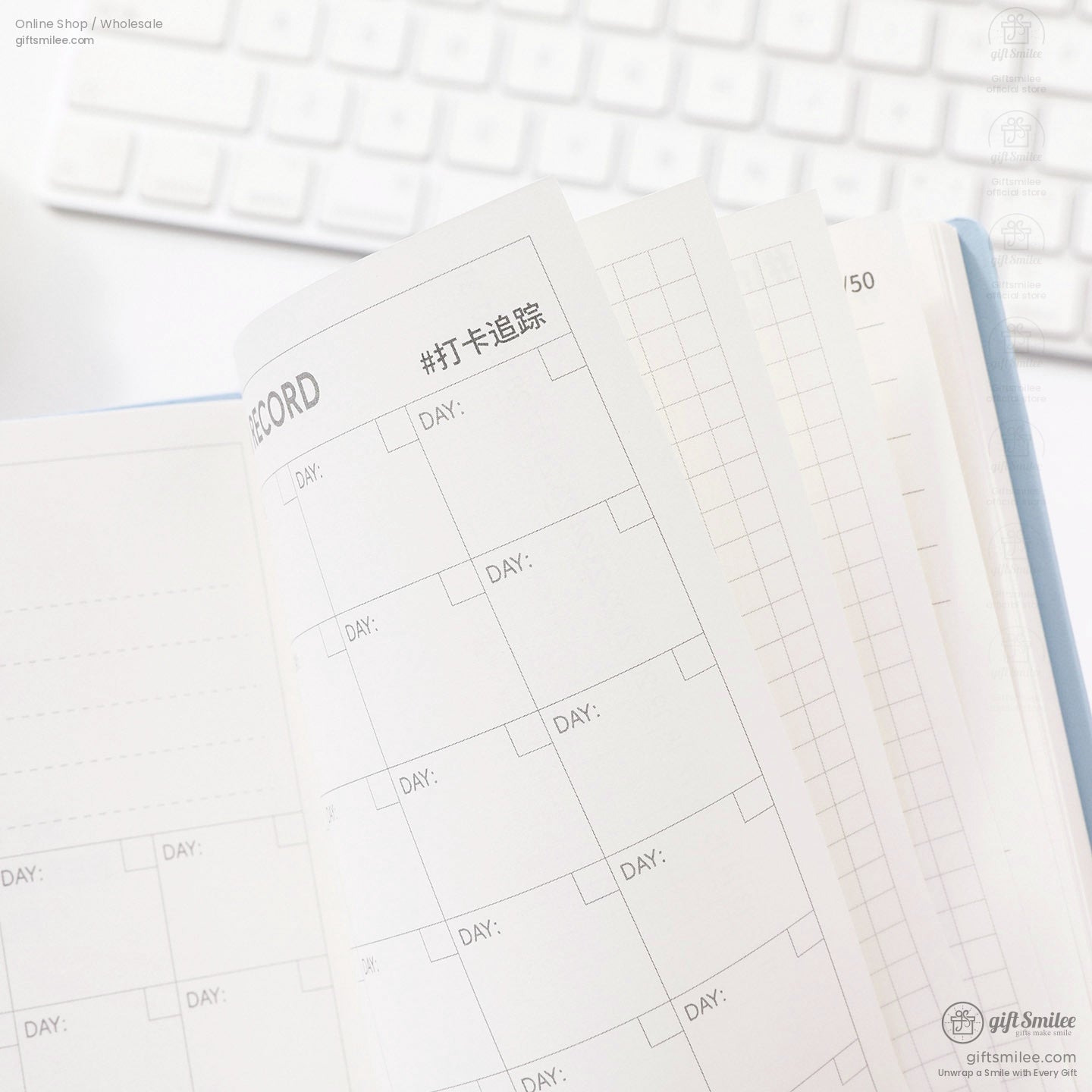 Minimalist planner notebook pages with daily record layout and grid sections on white desk keyboard background