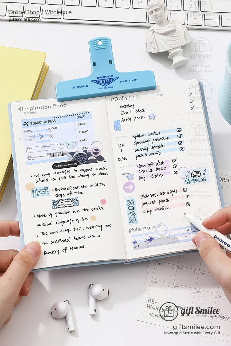Aesthetic flat lay of an open pastel-blue planner with handwritten to-do list and stickers on a white desk, surrounded by keyboard, clip, earbuds, and pen.