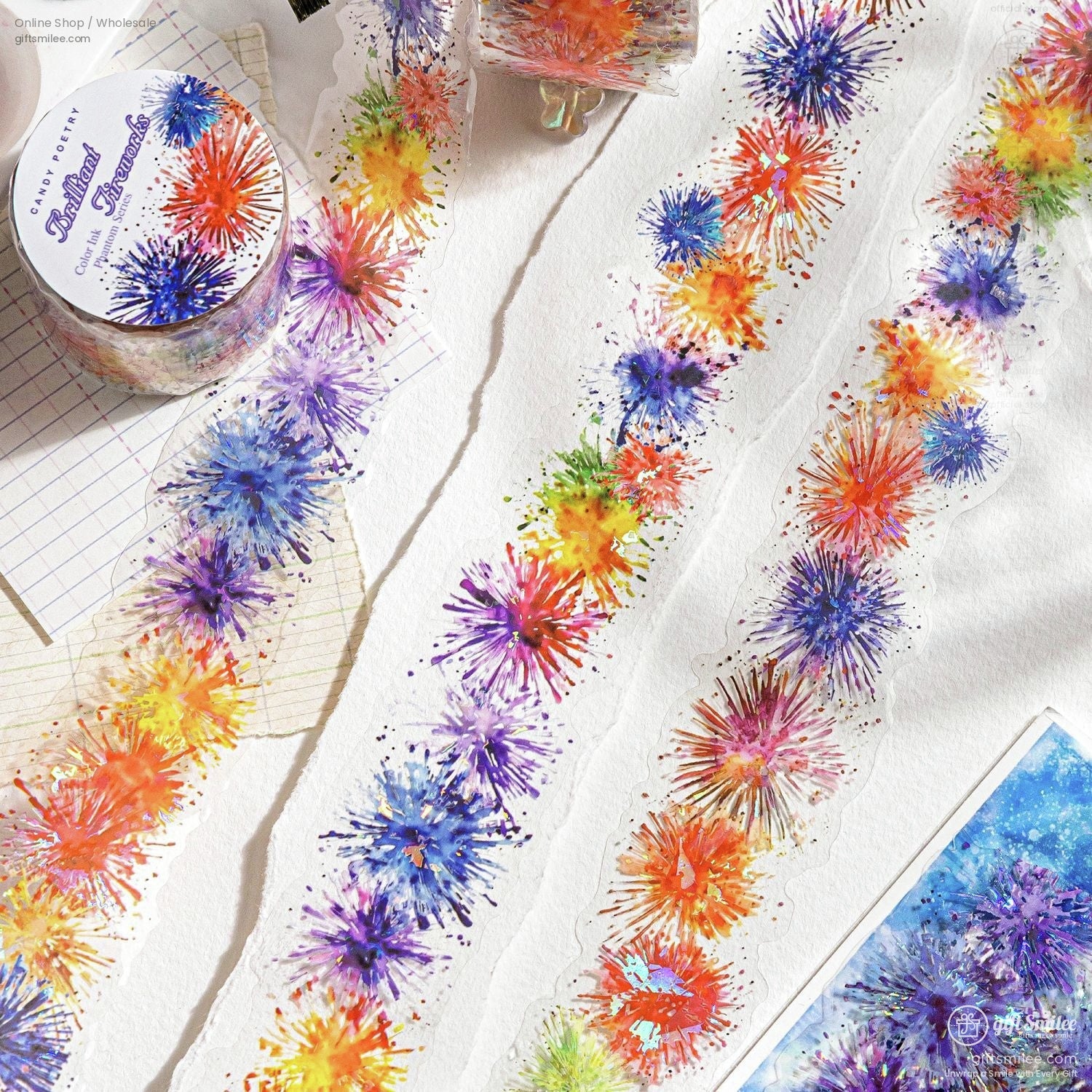 Colorful fireworks watercolor washi tape roll and strips displayed on white paper, festive decorative masking tape for crafts and journaling.