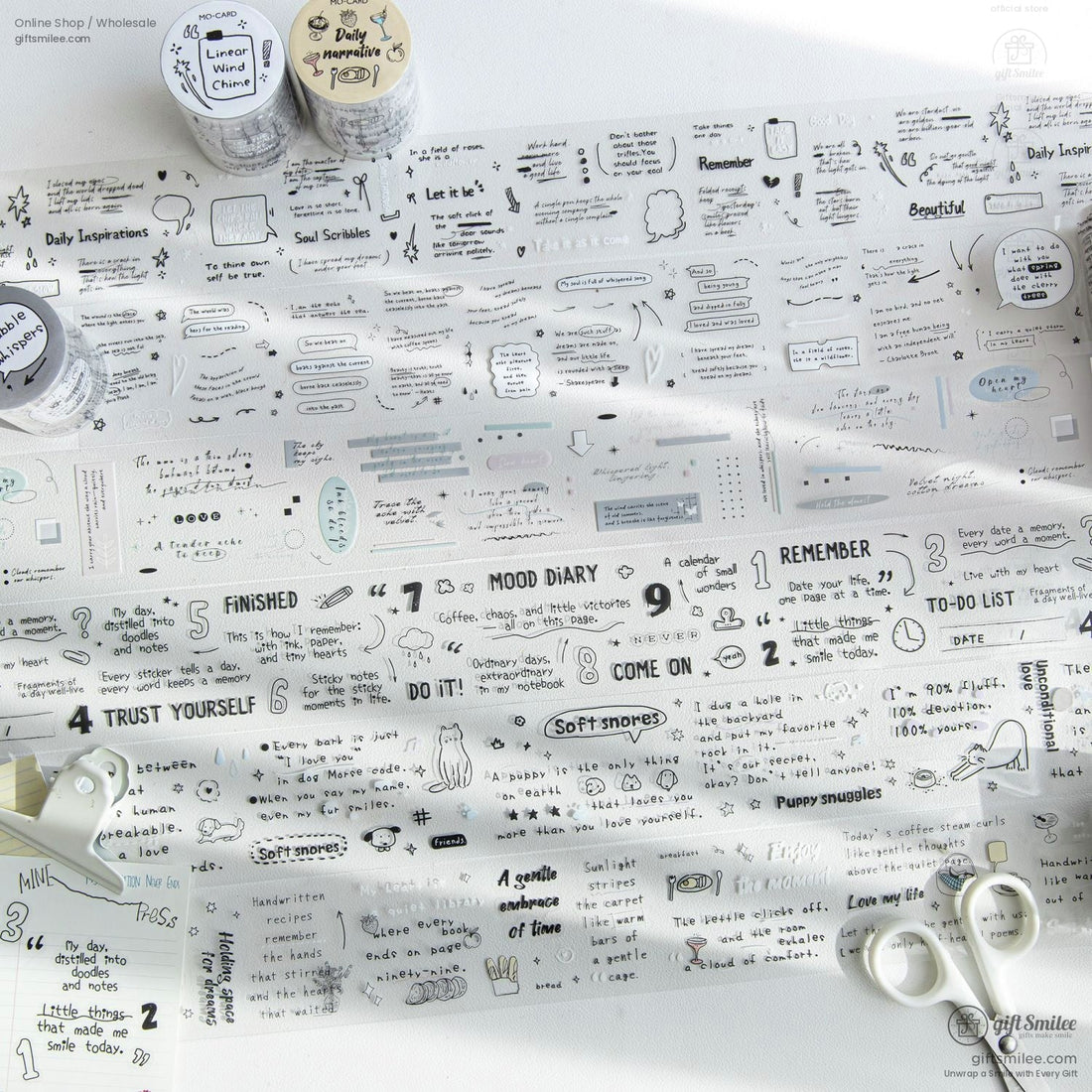 Transparent washi tape sheets with minimalist doodles and motivational quotes laid out on a desk with scissors and stationery.
