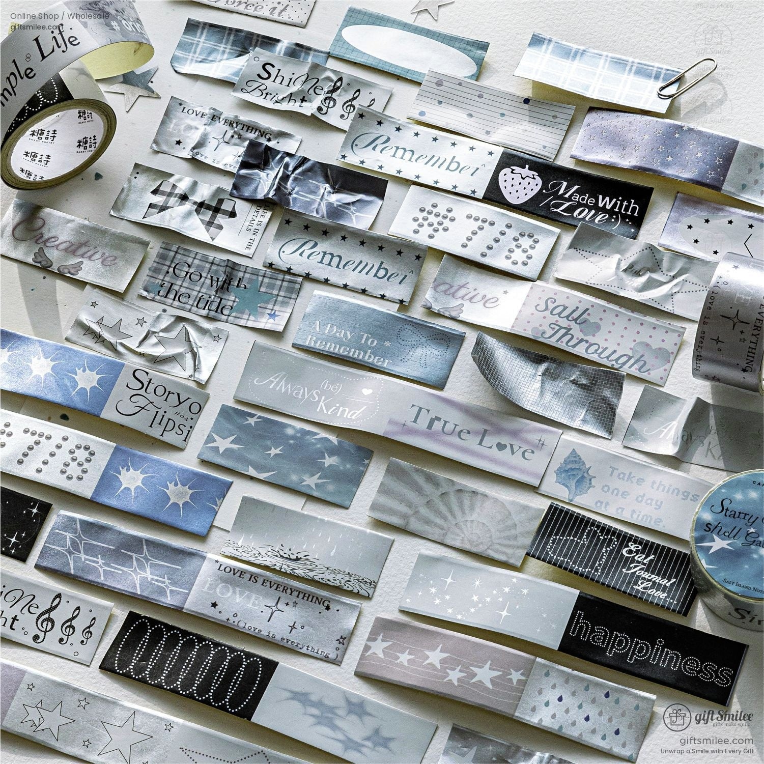Assorted silver and pastel washi tape labels with inspirational words and star patterns arranged on a white background.