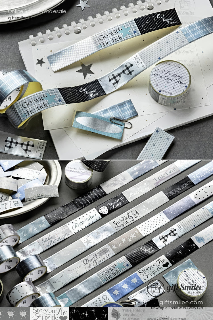 Blue and silver decorative washi tape set with winter-themed patterns and text laid out on a desk for scrapbooking and gift wrapping