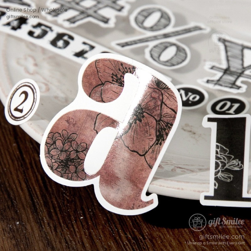 Brown floralpatterned decorative letter a sticker on a wooden surface with vintagestyle black and white designs nearby