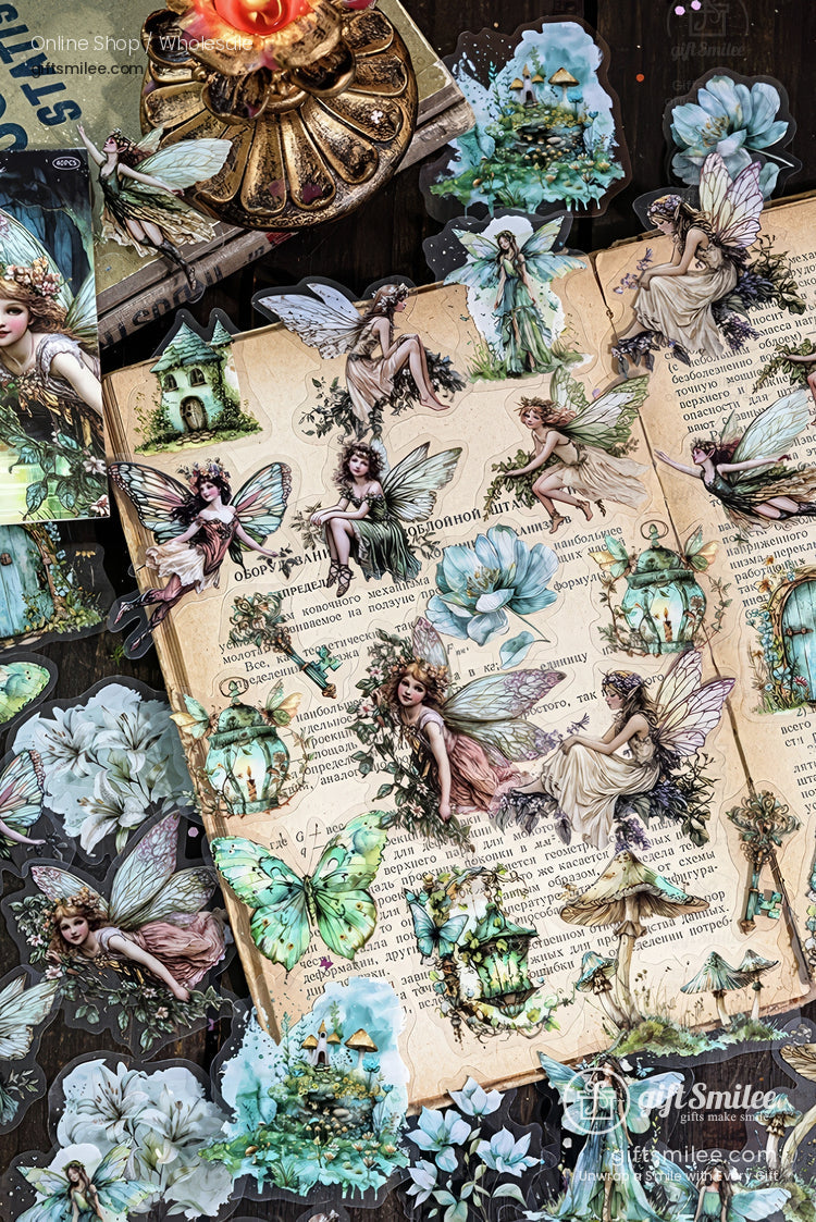 Vintage fairy stickers on an open book page with butterflies, flowers, and lantern illustrations in pastel green tones, scrapbook craft supplies.