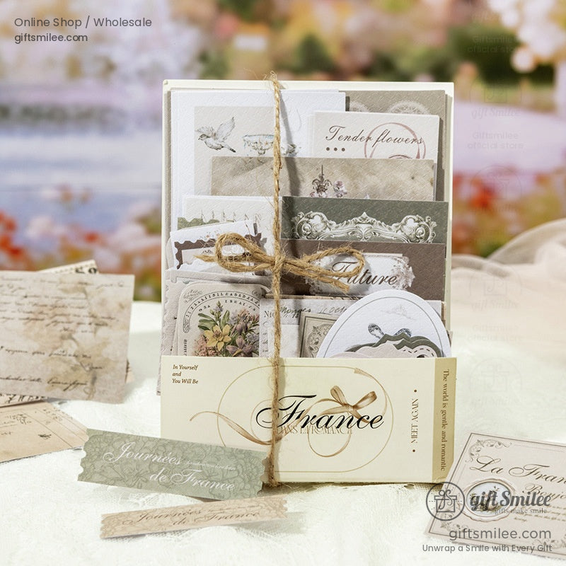 Vintage French-themed stationery set with assorted postcards, labels and tags tied with twine, ideal for scrapbooking and journaling.