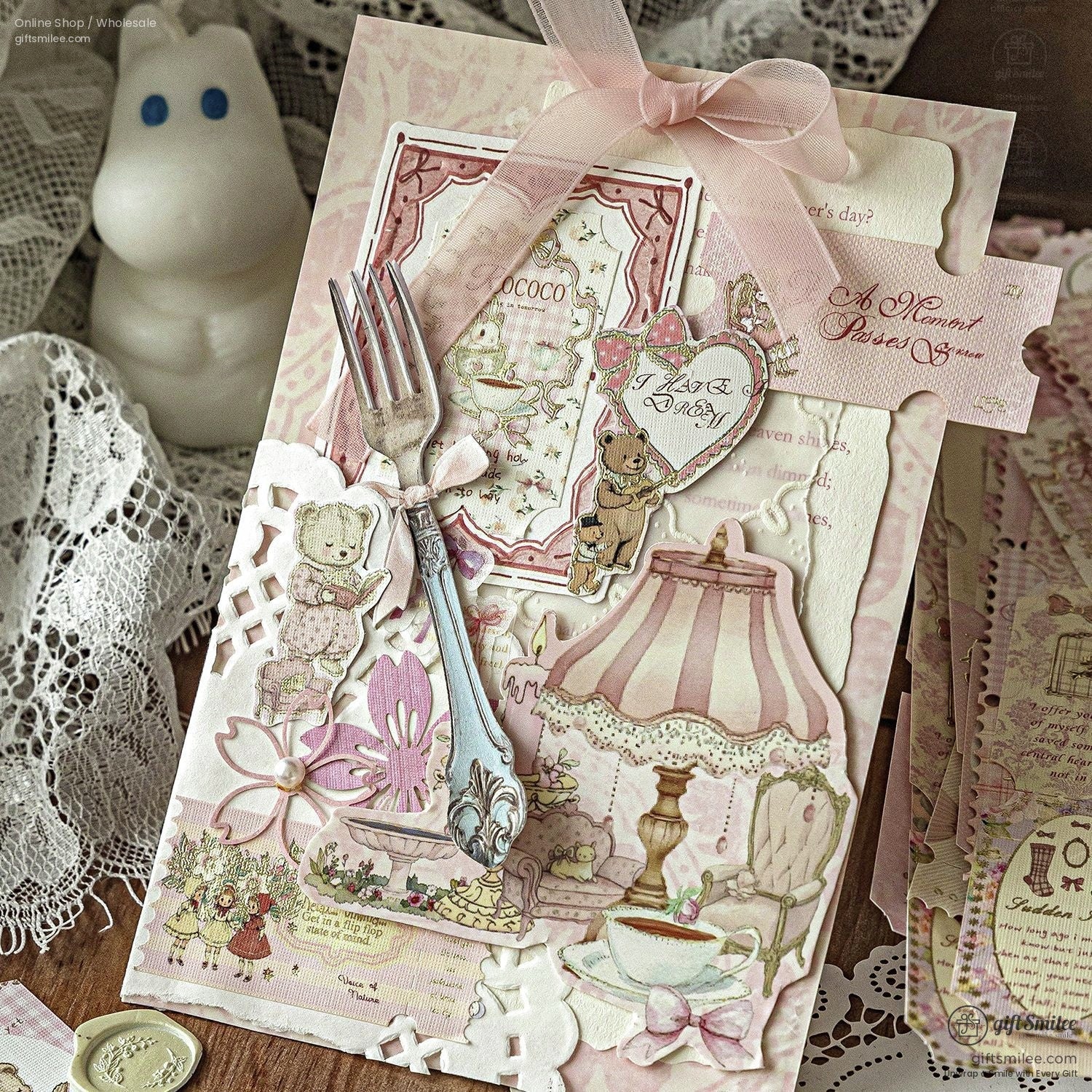 Vintage pink shabby chic scrapbook card with lace, ribbon bow, teddy bear and teacup embellishments on wooden table