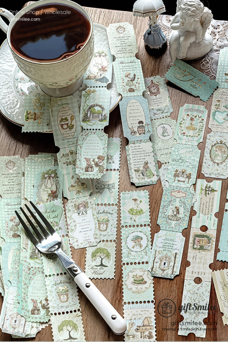 Vintage-style pastel journaling tickets and stickers spread on a wooden table beside a teacup and saucer, perfect for scrapbook or planner decoration.