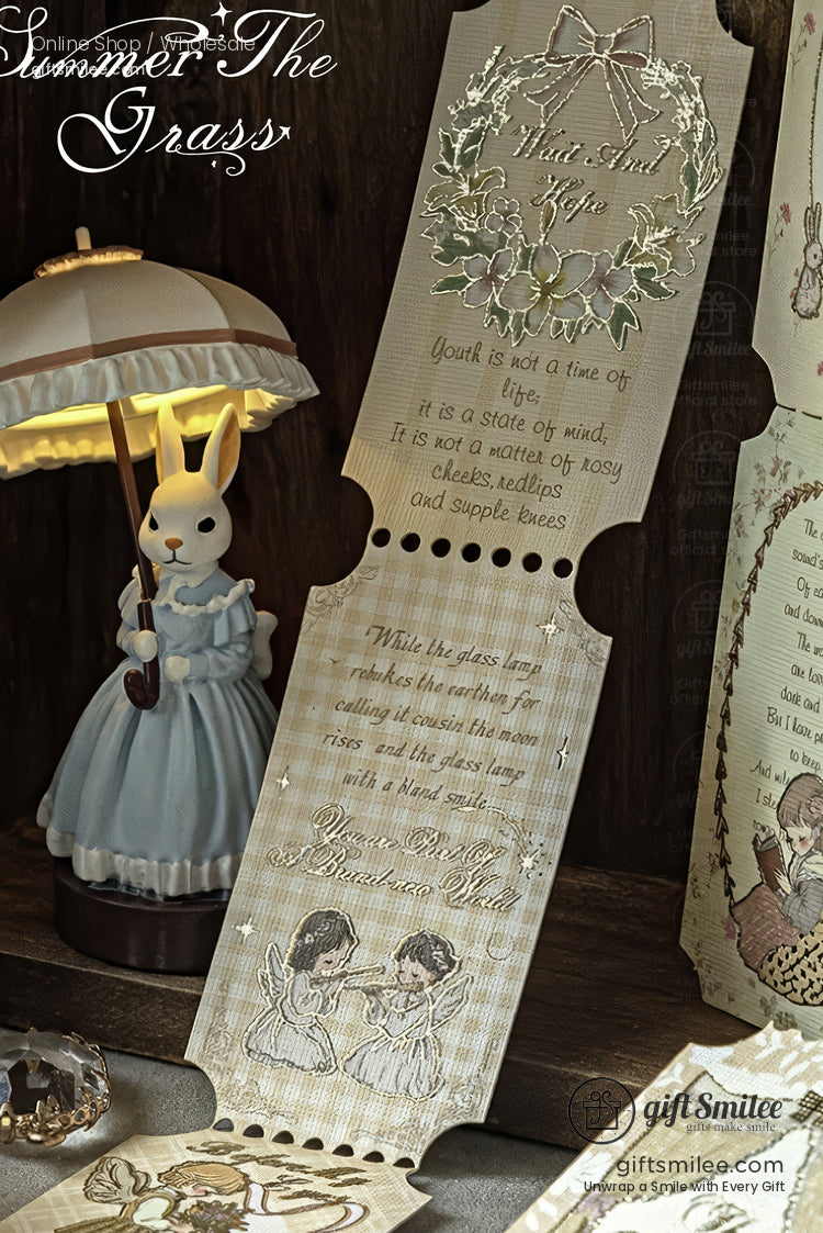 Vintage-inspired parchment bookmarks with floral wreaths and poetic quotes displayed beside a cute rabbit lamp on a wooden desk.
