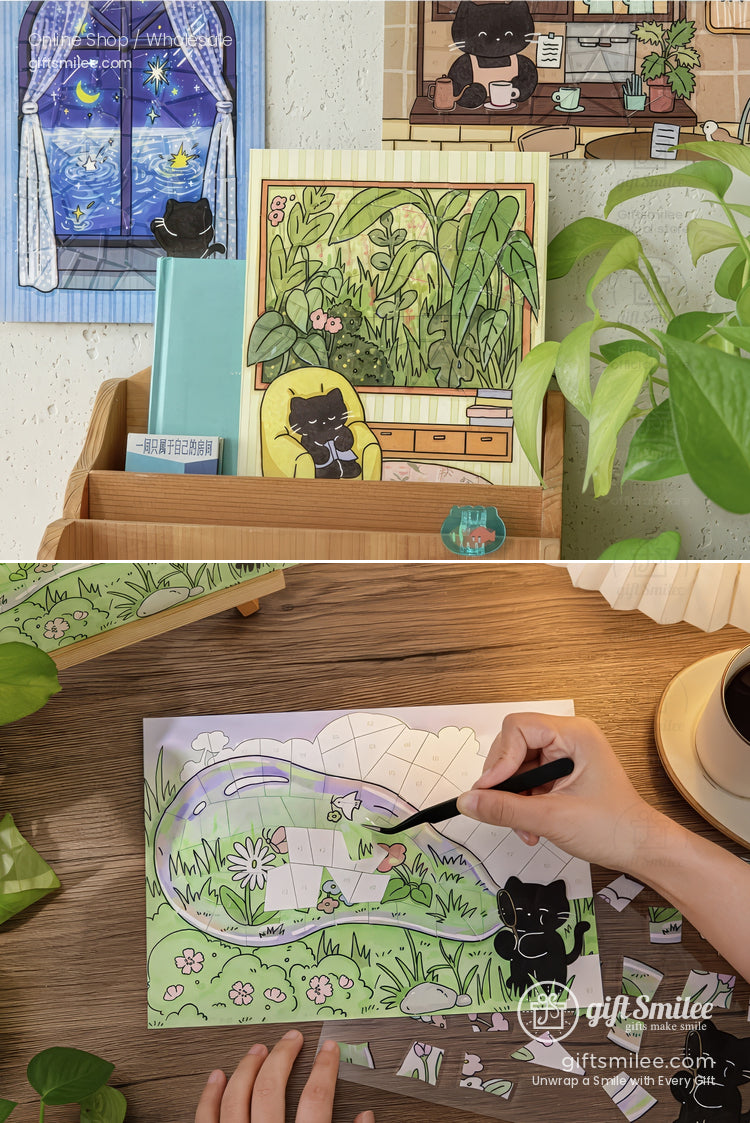 Cute black cat-themed stationery and art prints displayed on a desk, with a hand painting a whimsical garden scene illustration.
