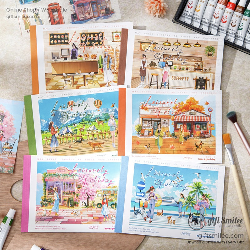 Cute watercolor travel postcards and stickers featuring scenic towns, hot air balloons, mountains, and pedestrians on a creative flat lay with paintbrush – scrapbooking stationery set by Giftsmilee.