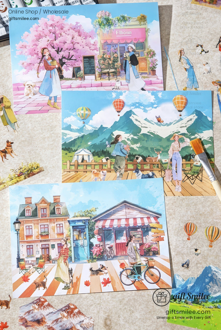 Colorful illustrated postcards of travel and city scenes with hot air balloons and floral streets, displayed flat lay for Giftsmilee shop.