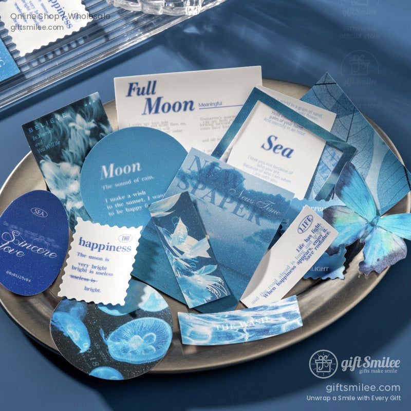 Assorted blue and white paper cards with moon sea and butterfly designs on a silver tray featuring elegant typography