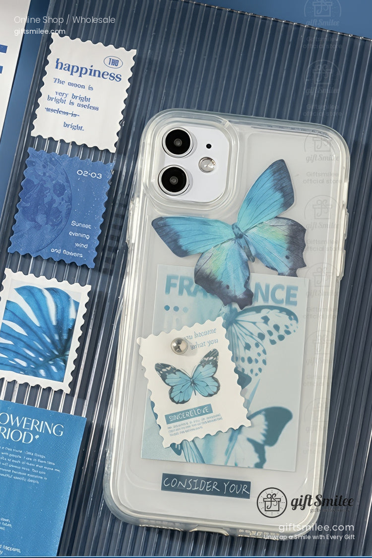 Clear phone case with blue butterfly design layered text accents and decorative stamps on a textured background