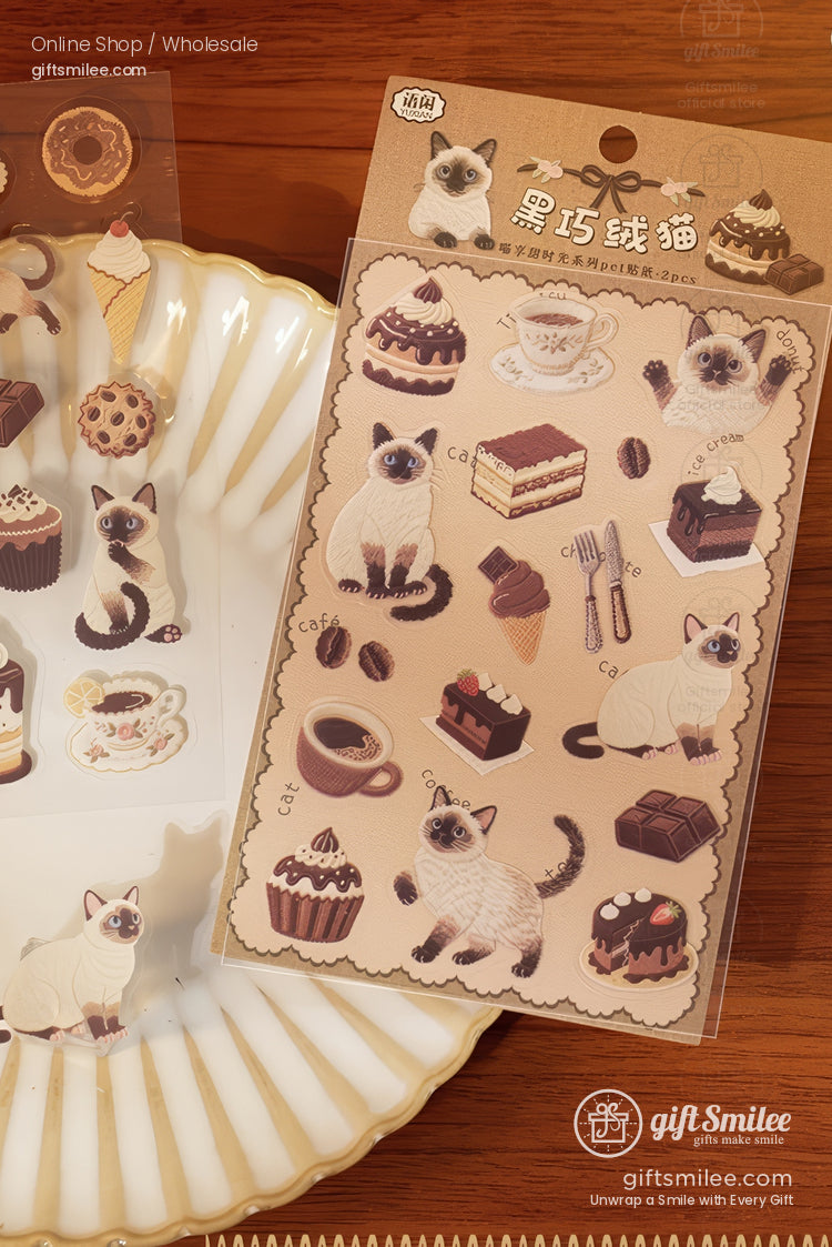Beige sticker sheet with Siamese cats chocolate desserts coffee and utensils on a wooden table next to a ceramic plate