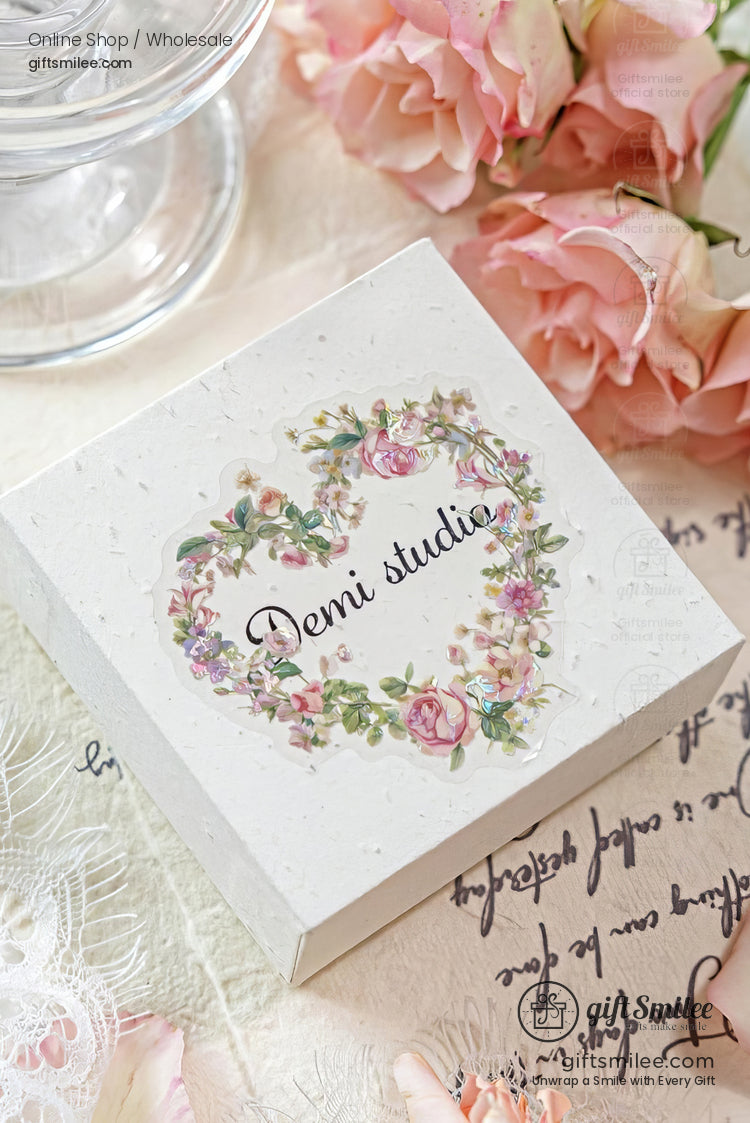White textured gift box with floral heart design Demi studio text surrounded by pink roses and delicate lace