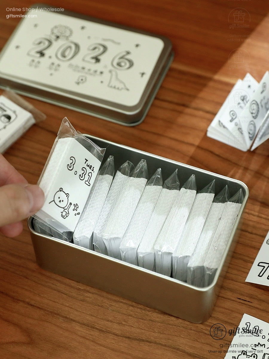Silver metal storage tin with 2026 design containing daily tearoff calendar sheets featuring cute bear illustrations