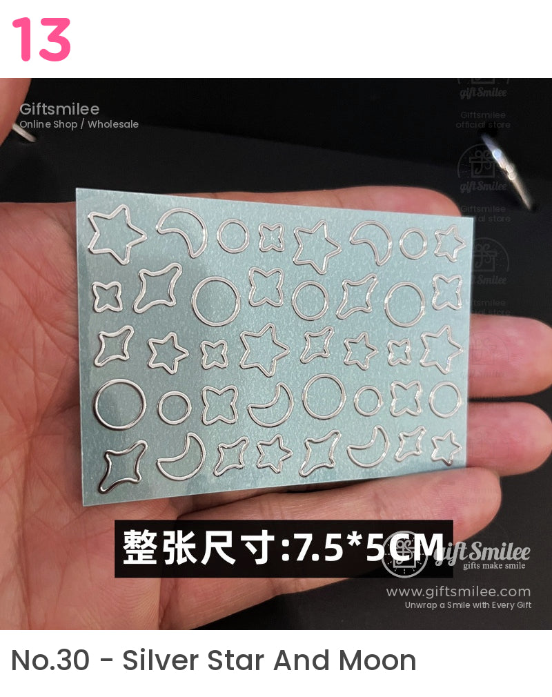 Silver metal diecut stencil sheet with stars moons circles and floral shapes on a glossy blue background 75x5 cm